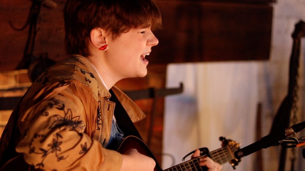 Young woman playing guitar and singing.