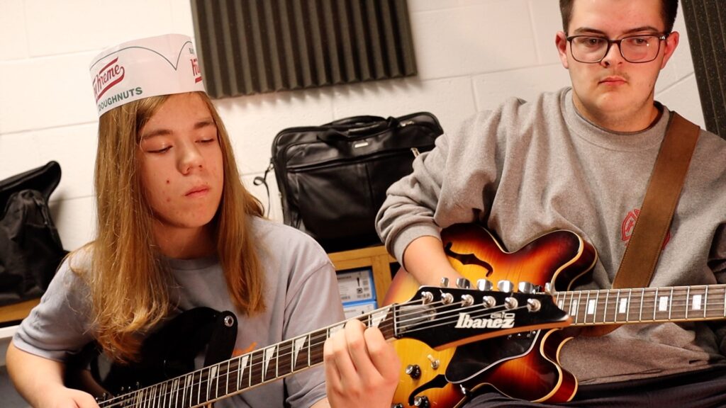 Two male high school students playing guitars