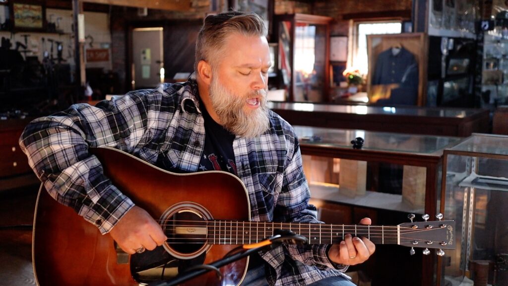 Middle aged man singing and playing guitar