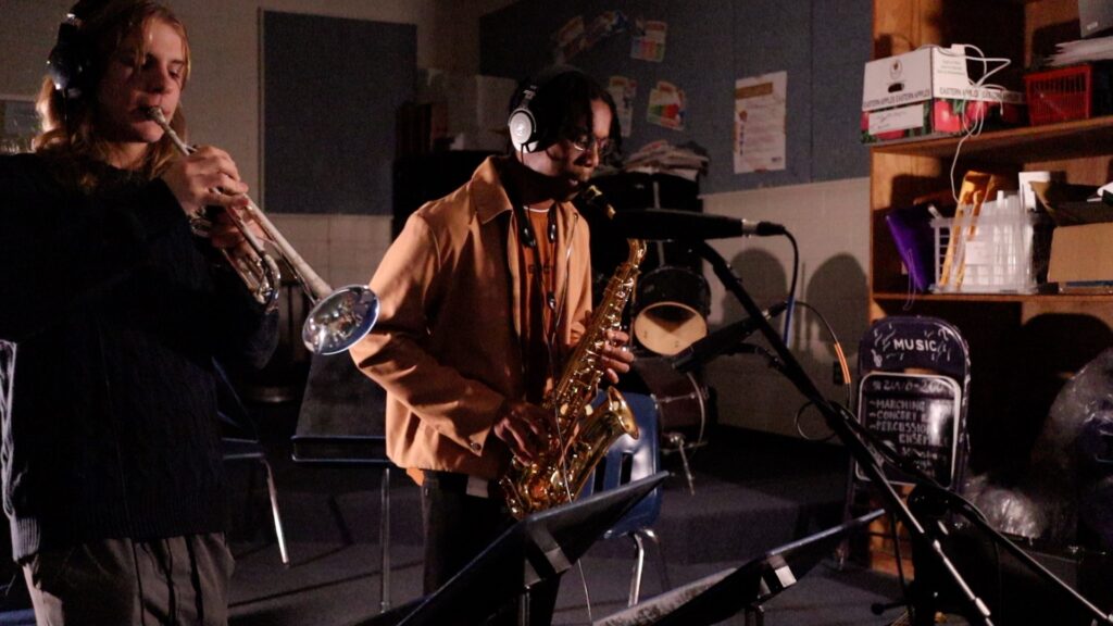 Two high school students playing trumpet and saxophone for recording